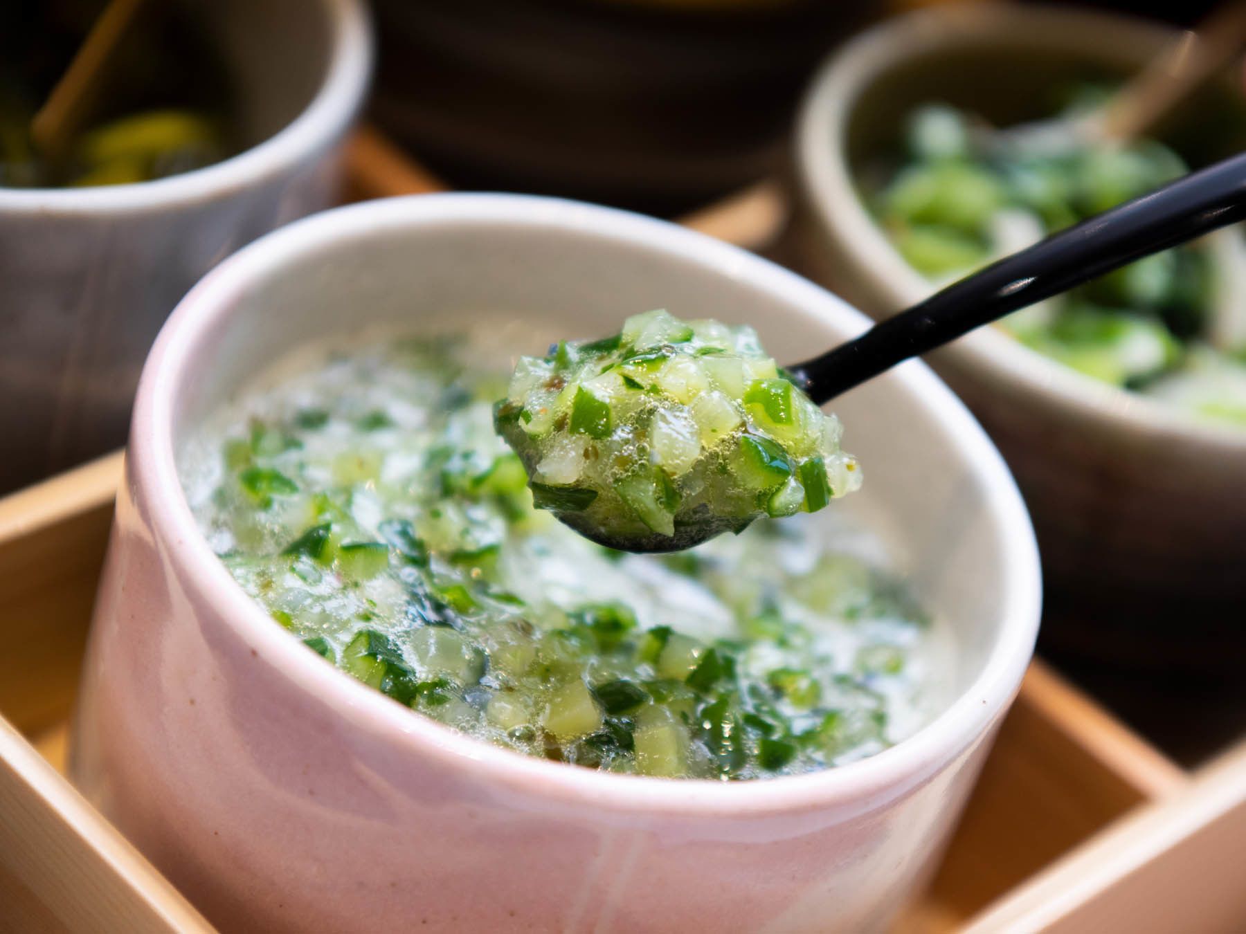 A bowl of soup with chopsticks lifting a portion.