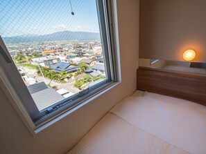 A hotel room with a large window offering a view of a cityscape and mountains. - Super Hotel Yamagata Sakuranbo Higashine Ekimae (Higashine)