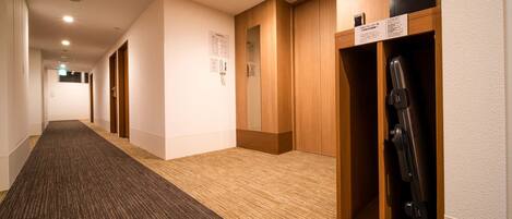 A hotel corridor with wooden lockers, a carpeted floor, and a sign indicating room number 7.