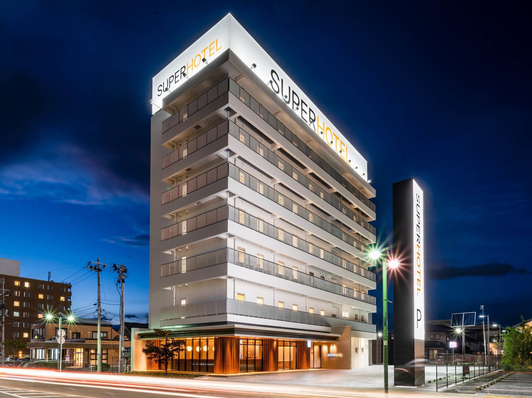 Un hotel de varios pisos con un llamativo letrero 'SuperHotel', múltiples balcones y un diseño arquitectónico moderno.