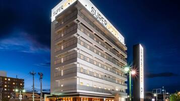 Un hotel de varios pisos con un llamativo letrero 'SuperHotel', múltiples balcones y un diseño arquitectónico moderno.