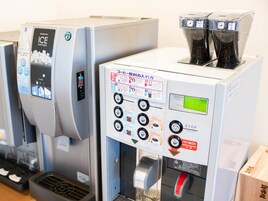 A coffee machine with multiple buttons and a digital display, next to an ice dispenser.