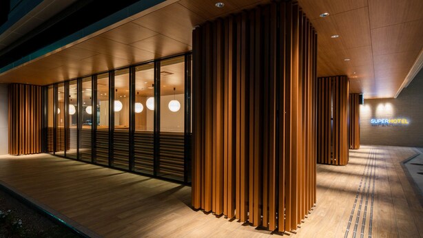 A modern hotel entrance with a wooden facade, glass doors, and a sign reading "Super Hotel". - Super Hotel Yamagata Sakuranbo Higashine Ekimae (Higashine)