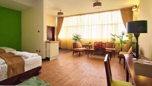 Ein Hotelzimmer mit einem Bett, einem Schreibtisch, einem Sessel, einer Couch, einem Couchtisch und einem Fernseher.