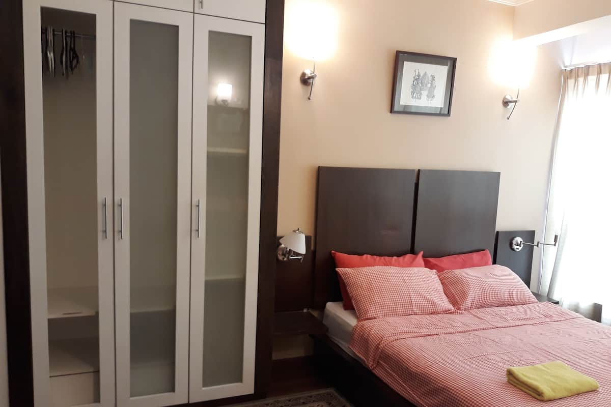 Una camera da letto con un letto, un armadio, un comodino e una lampada a parete.