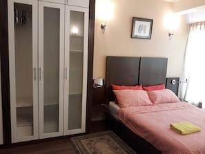 A bedroom with a bed, a wardrobe, a nightstand, and a wall-mounted lamp. - Sarang Mutiara Apartment (Kuala Lumpur)