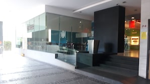 Una entrada de edificio moderna con puertas de vidrio, una escalera y un área de descanso.