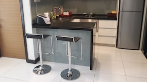 Una cocina moderna con una isla central, electrodomésticos de acero inoxidable y dos taburetes de bar.
