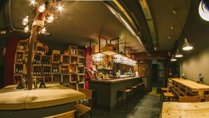 Un bar acogedor con muebles de madera, una barra central y estantes llenos de botellas.