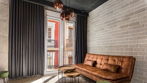 Una sala moderna con un sofá de cuero marrón, dos mesitas de madera y un sillón verde.