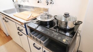 A kitchen with a modern stove, a sink, and a wooden cutting board. - Mainichi Building Osaka (Osaka)