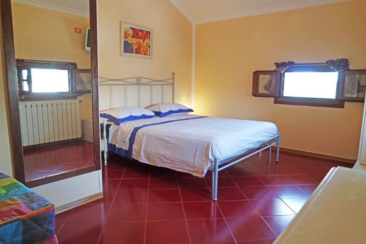 Une chambre avec un lit, un radiateur, une fenêtre et un tableau au mur.