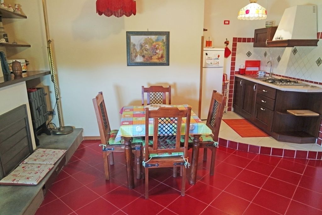 Een eethoek met een tafel voor vier personen, omringd door houten stoelen. Een kleurrijke tafelkleed bedekt de tafel.