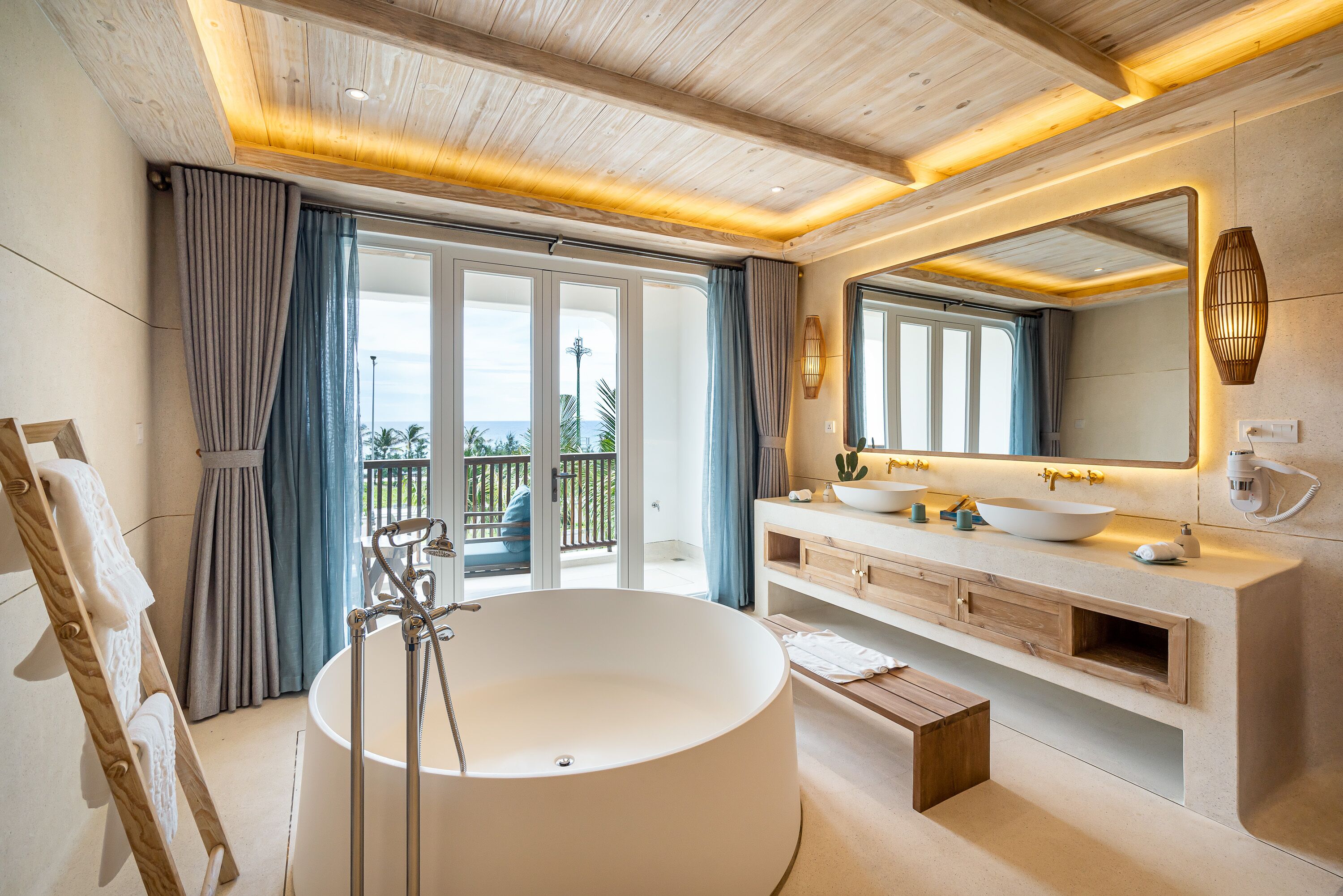 A modern bathroom with a freestanding bathtub, a large mirror, and a vanity with dual sinks.