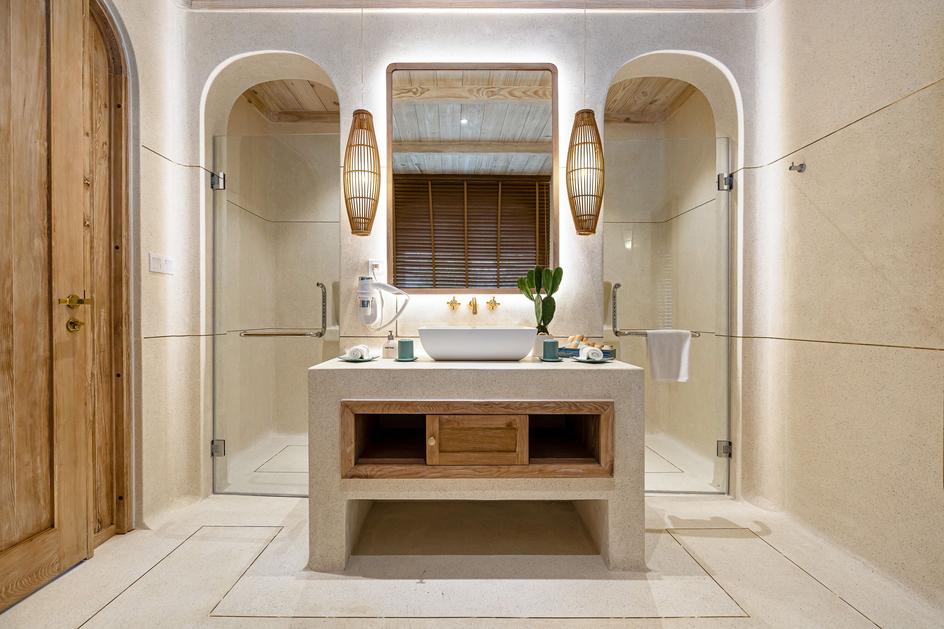A bathroom with a large mirror, wooden vanity, and two wall-mounted lights.