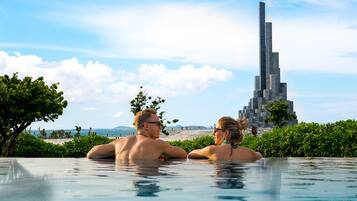 A couple in a swimming pool with a modern skyscraper in the background.