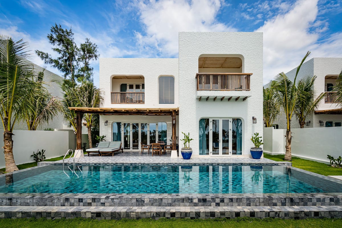 A modern house with a swimming pool, a covered patio, and a two-story balcony.