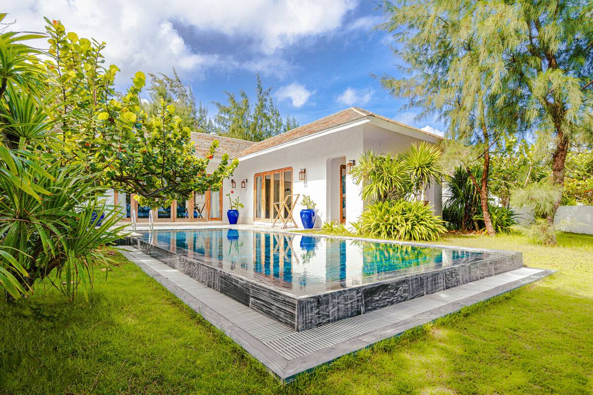 A modern house with a swimming pool surrounded by lush greenery.