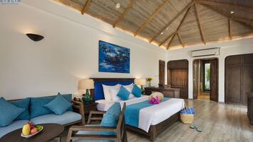 A spacious bedroom with a large bed, a sofa, and a small table. There is a painting on the wall and a wooden ceiling.