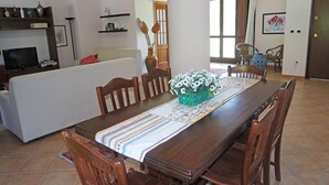 A dining area with a long wooden table, chairs, and a vase of flowers. - Villa Kalithea (Montecorice)