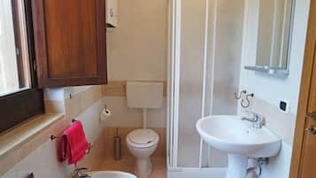 Casa de banho com sanita, bidé, lavatório e chuveiro.