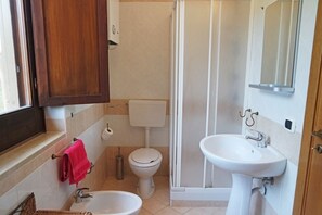 A bathroom with a toilet, bidet, sink, and shower. - Villa Kalithea (Montecorice)