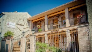 Edifici de pedra tradicional amb un balcó, un rètol que indica un restaurant i una reixa de ferro.
