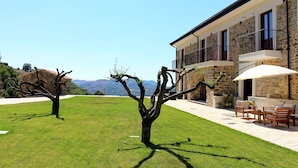A stone building with a balcony, a lawn with two trees, and a view of mountains. - Casale Acquaviva (Torchiara)