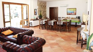 A spacious living area with a leather sofa, dining table, and chairs. There is a stone wall, a wooden door, and a painting on the wall. - Casale Acquaviva (Torchiara)
