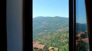 Vista desde una ventana con paisaje montañoso y edificios en la base.