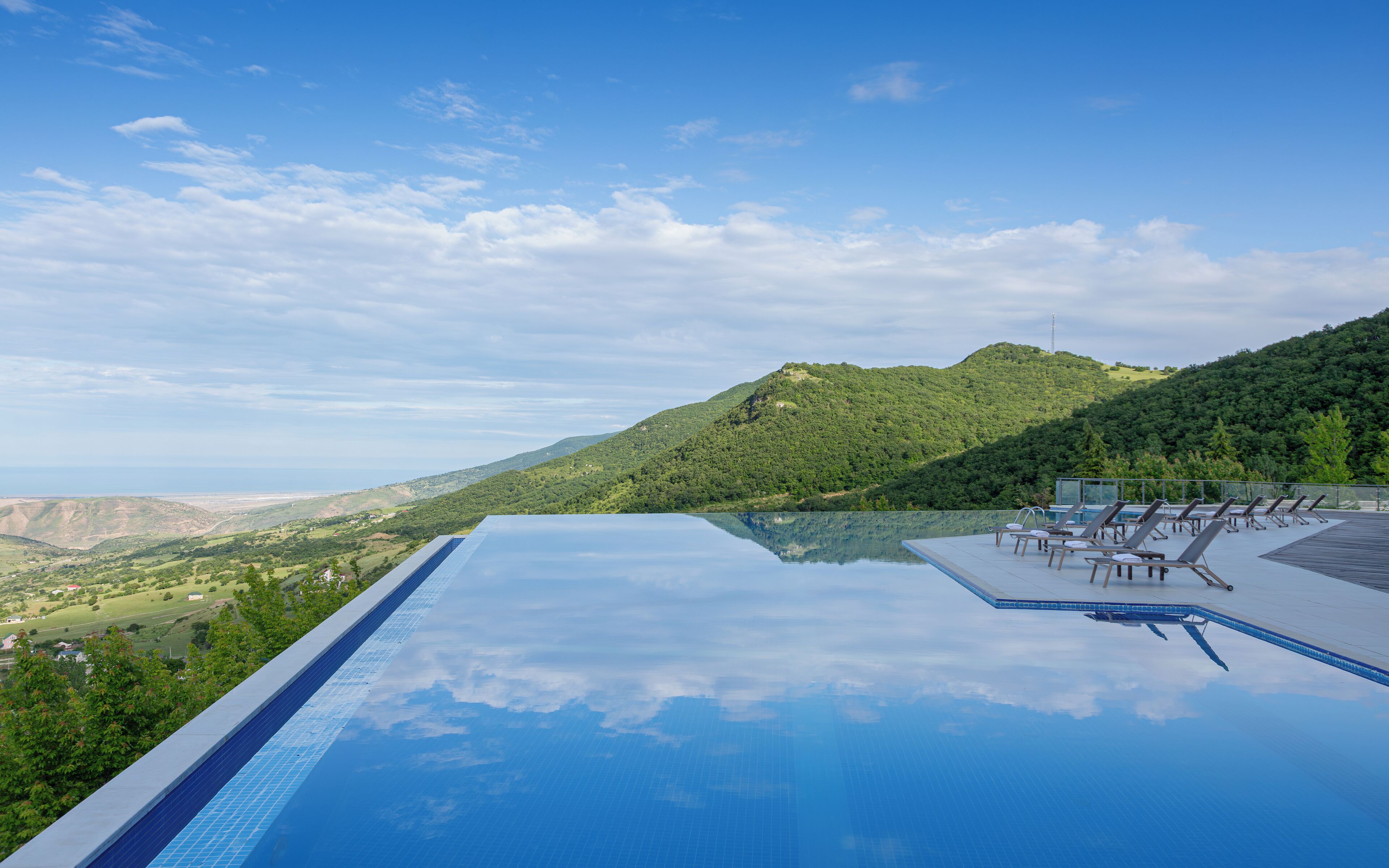 Ein Infinity-Pool mit freiem Blick auf eine gebirgige Landschaft und den weiten Horizont.