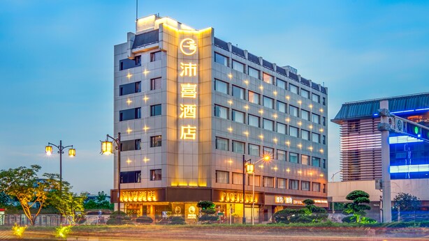 Ein mehrgeschossiges Hotel mit beleuchteter Beschilderung, einer modernen Fassade und einer gepflegten Außenansicht.