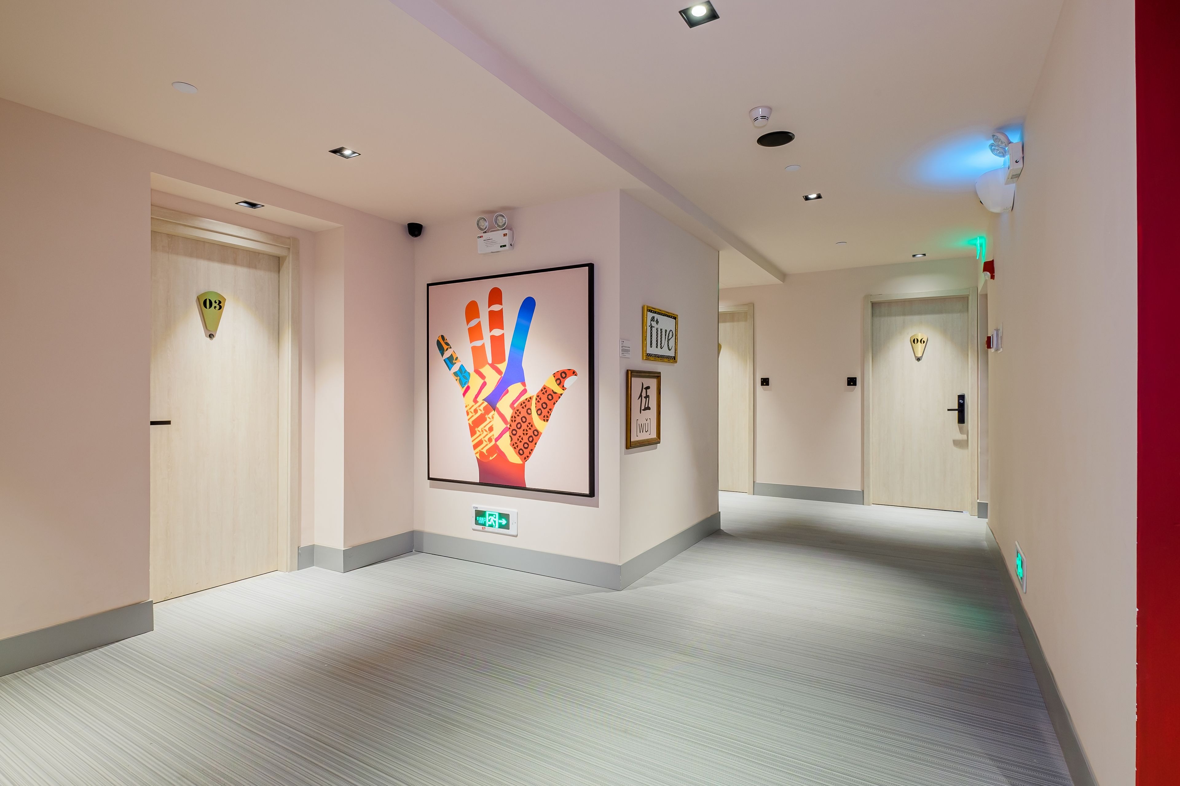 Een hotelgang met een handafdruk kunstwerk, deuren met kamer nummers, en een schoon, modern design.