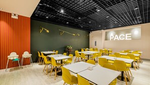 Ein Konferenzraum mit gelben Stühlen und weißen Tischen, einem schwarzen Raster an der Decke und einem 'PACE'-Schild an der Wand.