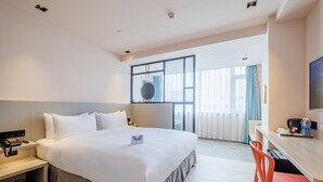 Ein Hotelzimmer mit einem großen Bett, einem Nachttisch und einem Schreibtisch mit Stuhl.