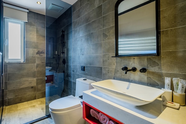 Un baño moderno con un lavamanos grande de color blanco, una cabina de ducha de vidrio y un inodoro.