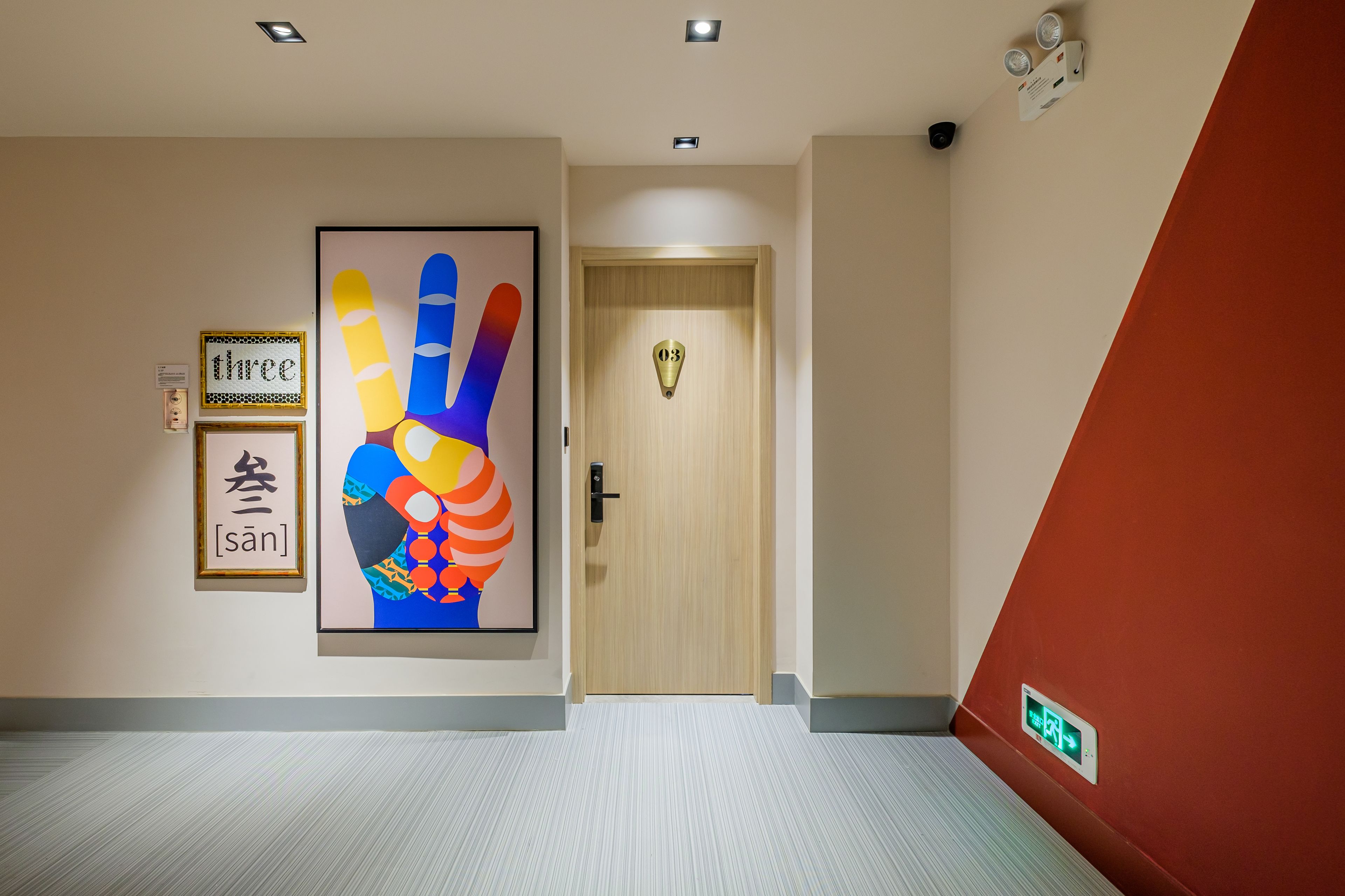 A hallway with a wooden door marked '03', a colorful handprint artwork, and a 'three' sign with Chinese characters.