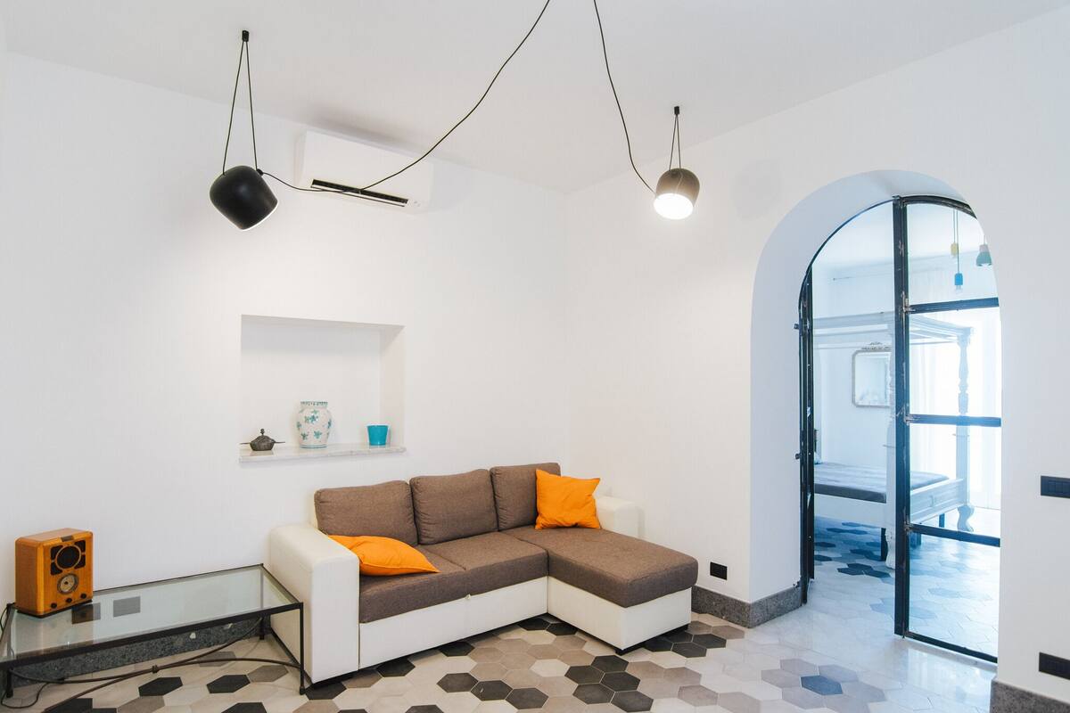 A modern living room with a sectional sofa, a glass coffee table, and a small wooden speaker.