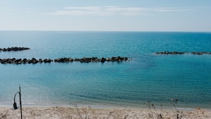 A beach with calm waters, a rocky breakwater, and a sandy shore. - La Concha Suites (Pollica)