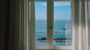 A view from a window with curtains, overlooking a clear blue sea and a rocky shoreline. - La Concha Suites (Pollica)