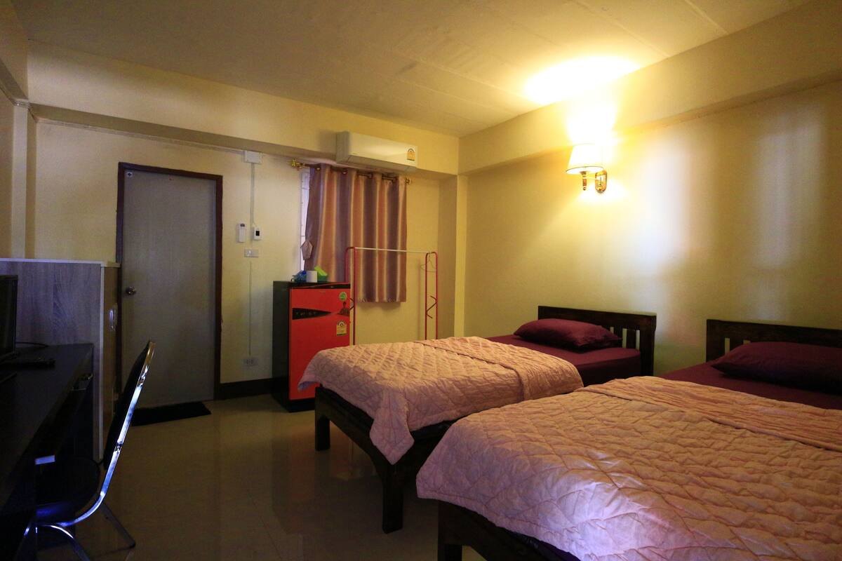 Une chambre d’hôtel avec deux lits, un bureau, une chaise, une armoire et une salle de bain.