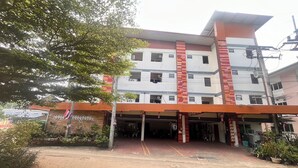 Un edificio de varios pisos con un vestíbulo cubierto y un camino de tierra.