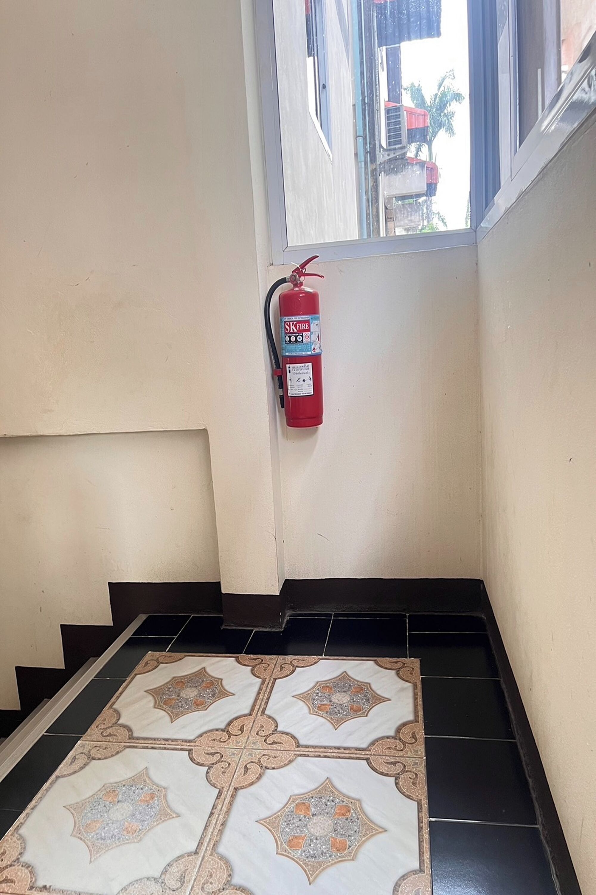 A fire extinguisher mounted on a wall in a stairwell.
