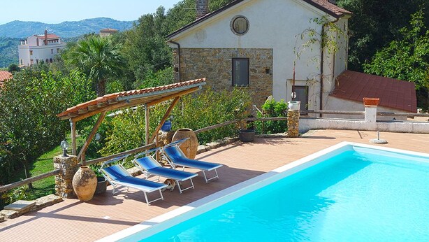 A pool area with lounge chairs, a pergola, and a stone building with a red roof. - Villa Acquavella (Casal Velino)