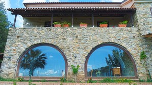 A stone building with two large arched windows and a balcony with potted plants. - Villa Acquavella (Casal Velino)