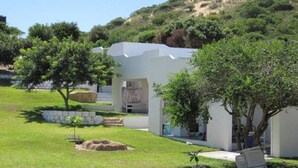 A modern white building with a covered outdoor seating area, surrounded by lush greenery and trees. - Serenity Nhabanga (Praia do Bilene)