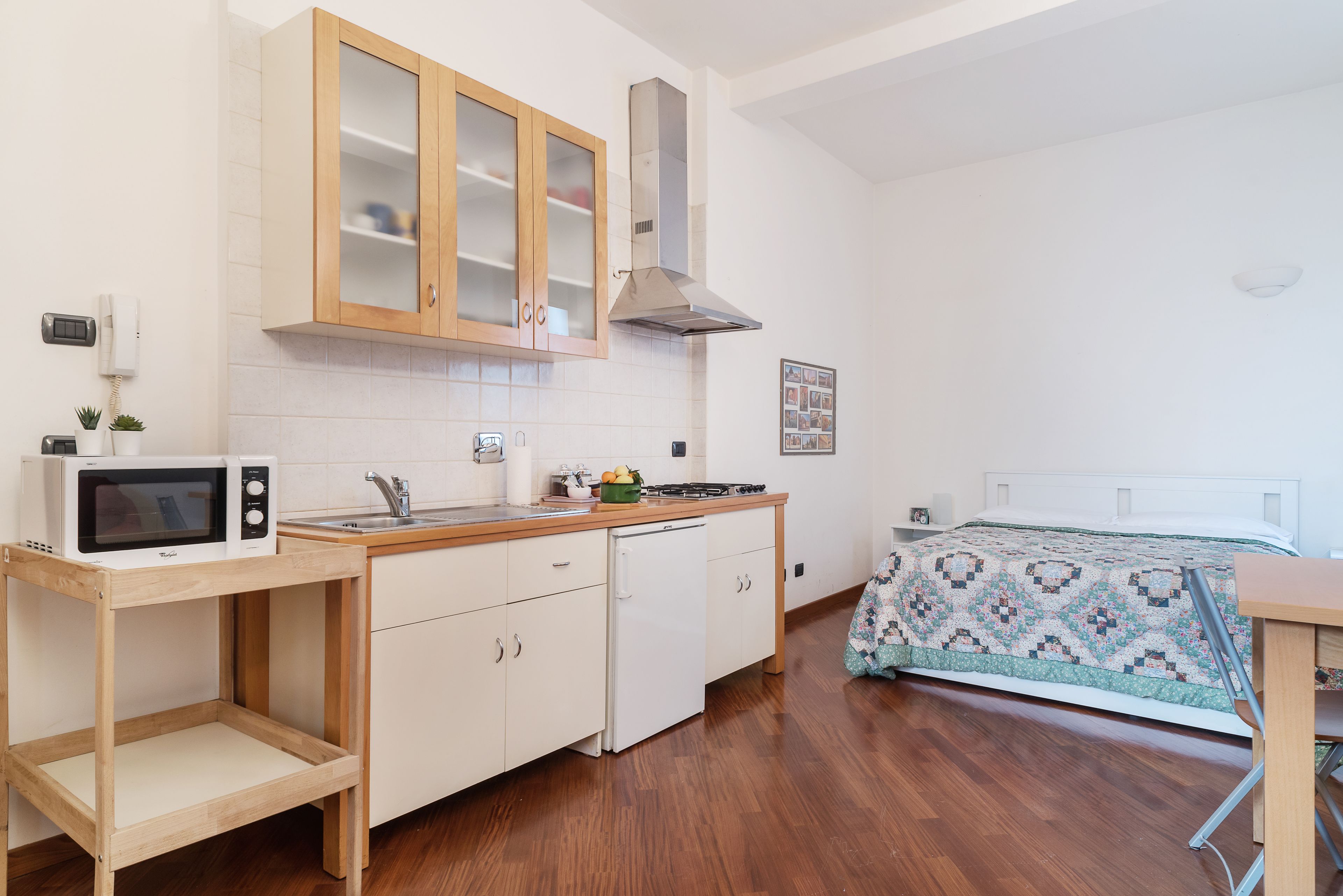 Une cuisine compacte avec des meubles en bois, un four à micro-ondes, un évier et un petit réfrigérateur.