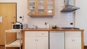 Una cocina compacta con armarios de madera, microondas, pileta, estufa y lavavajillas.