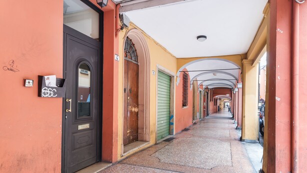 Un pasillo estrecho con varias puertas y ventanas que dan a habitaciones individuales.