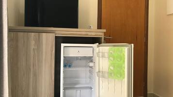 Uma geladeira compacta com topo de madeira, compartimento congelador embutido e porta transparente.